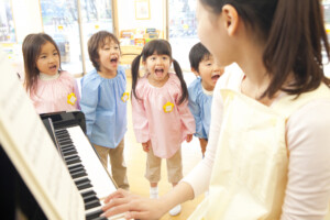 ピアノを弾く保育士と子供たち